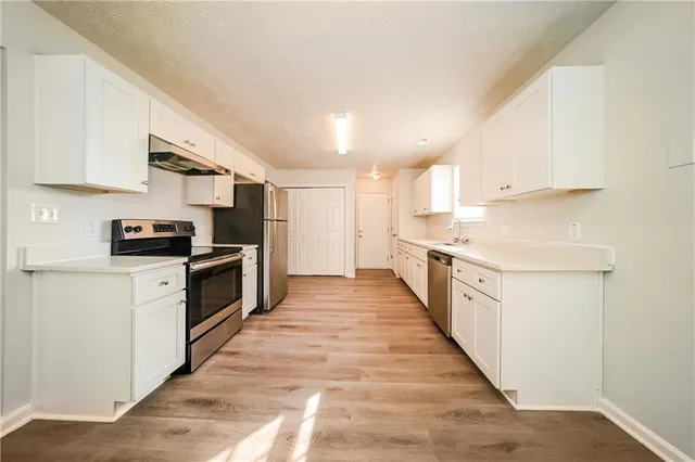 a kitchen with granite countertop a stove top oven a sink dishwasher and a refrigerator with wooden floor