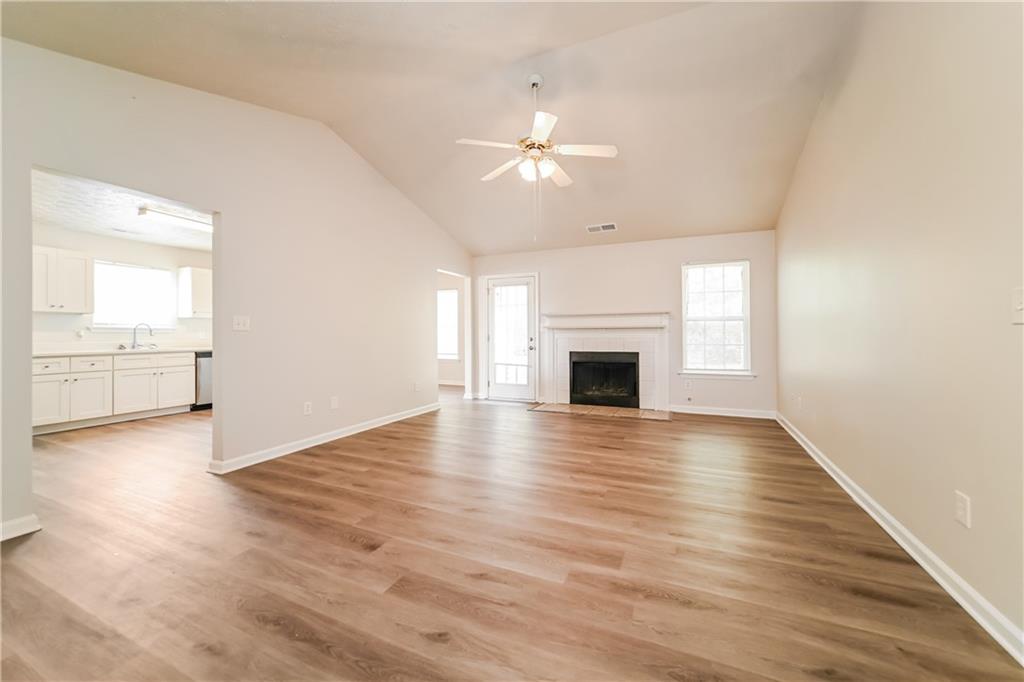 11171 Knotty Pine Place Hampton, GA 30228 - Photo 9 of 26 an empty room with wooden floor fireplace and windows
