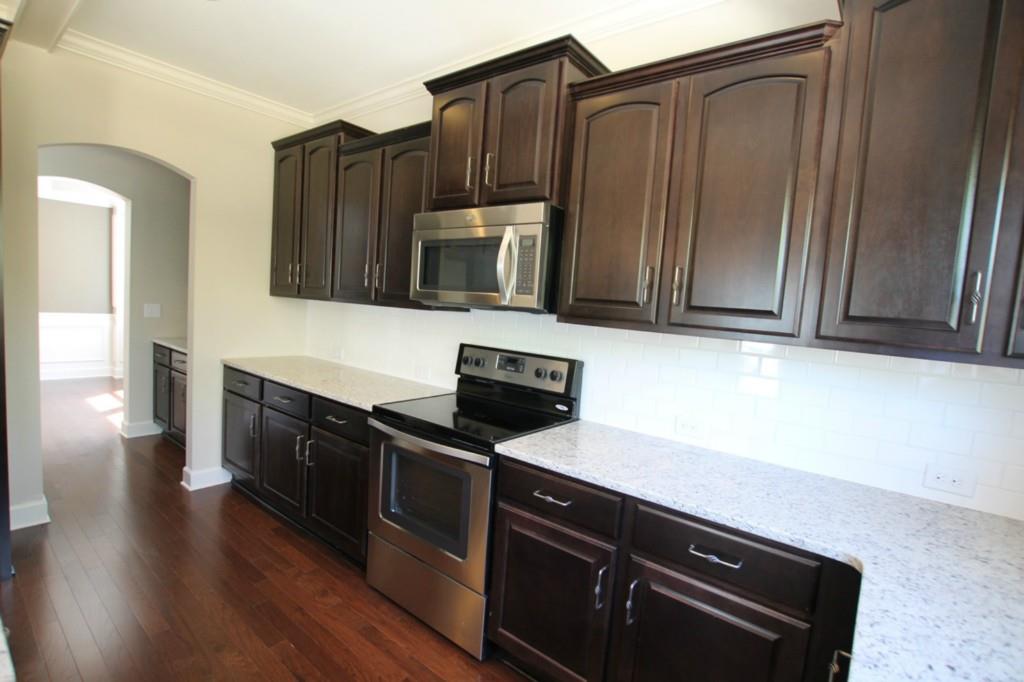 2191 Bluebell Way, Unit 11 Tega Cay, SC 29708 - Photo 4 of 14 a kitchen with granite countertop wooden cabinets and stainless steel appliances