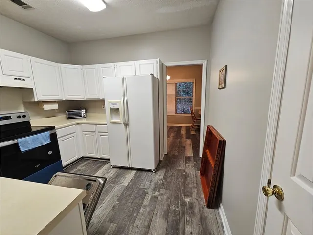 a kitchen with white cabinets and refrigerator