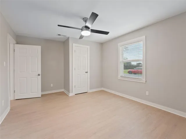 an empty room with closet and ceiling fan