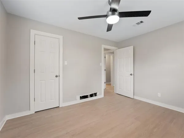 a view of an empty room and chandelier fan