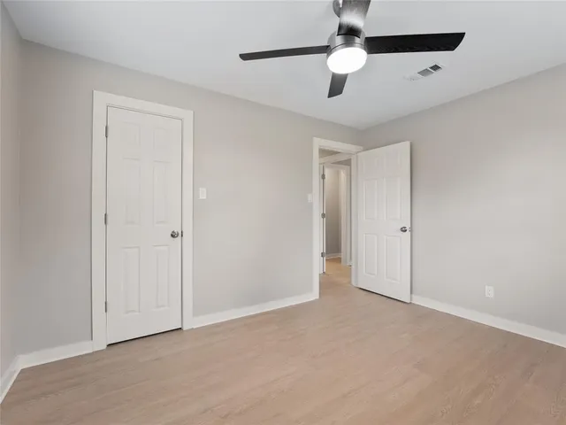 an empty room with a window and a ceiling fan