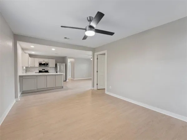 a view of a kitchen with a refrigerator a ceiling fan and stainless steel appliances