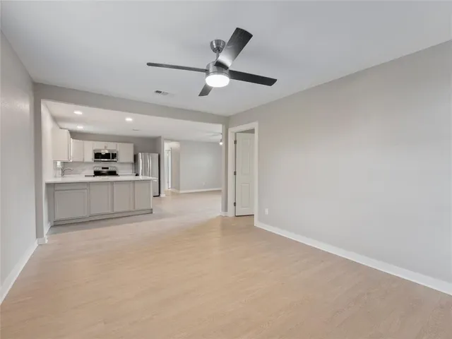 a view of a kitchen with a refrigerator a ceiling fan and stainless steel appliances