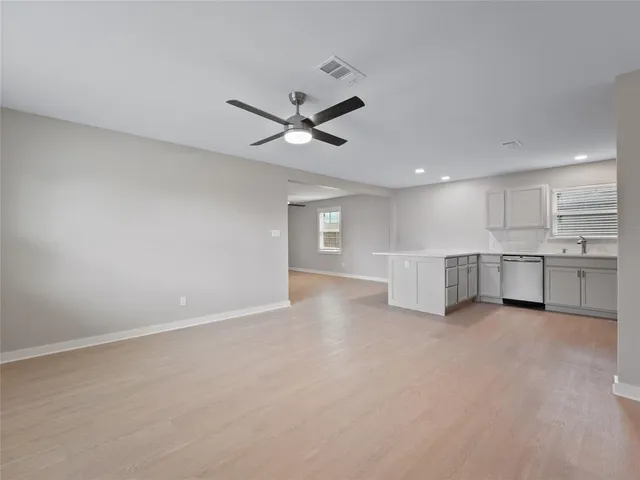 an empty room with ceiling fan and windows