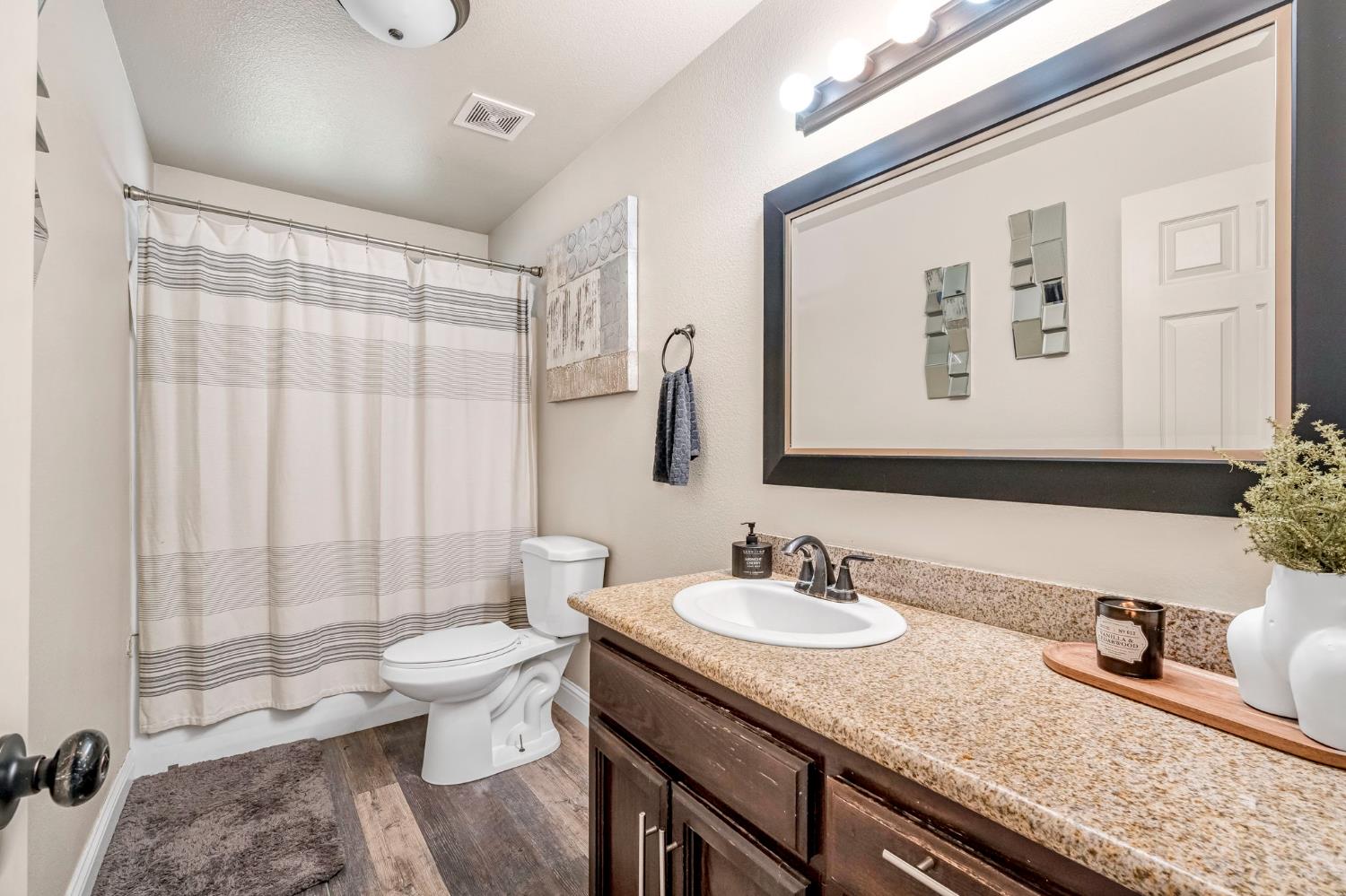 25802 El Monte Way Madera, CA 93638 - Photo 22 of 39 full bathroom with vanity, dark wood-type flooring, and shower / bath combo with shower curtain