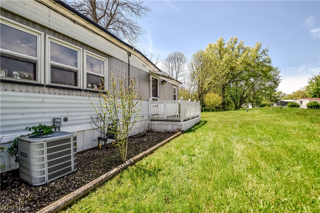 112 Lakeside Way Southwest Warren, OH 44481 - Photo 15 of 16 Expansive green space featuring a white privacy deck with railings, a building exterior with horizontal siding, multiple windows, and a foundation planting bed