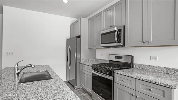 a kitchen with granite countertop a sink a stove and cabinets