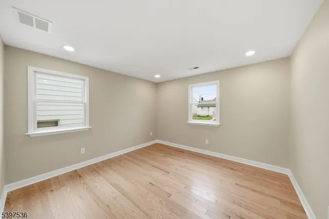 a view of a big room with wooden floor and windows