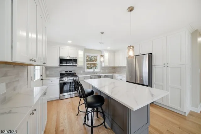 a kitchen with stainless steel appliances kitchen island a table chairs refrigerator and sink
