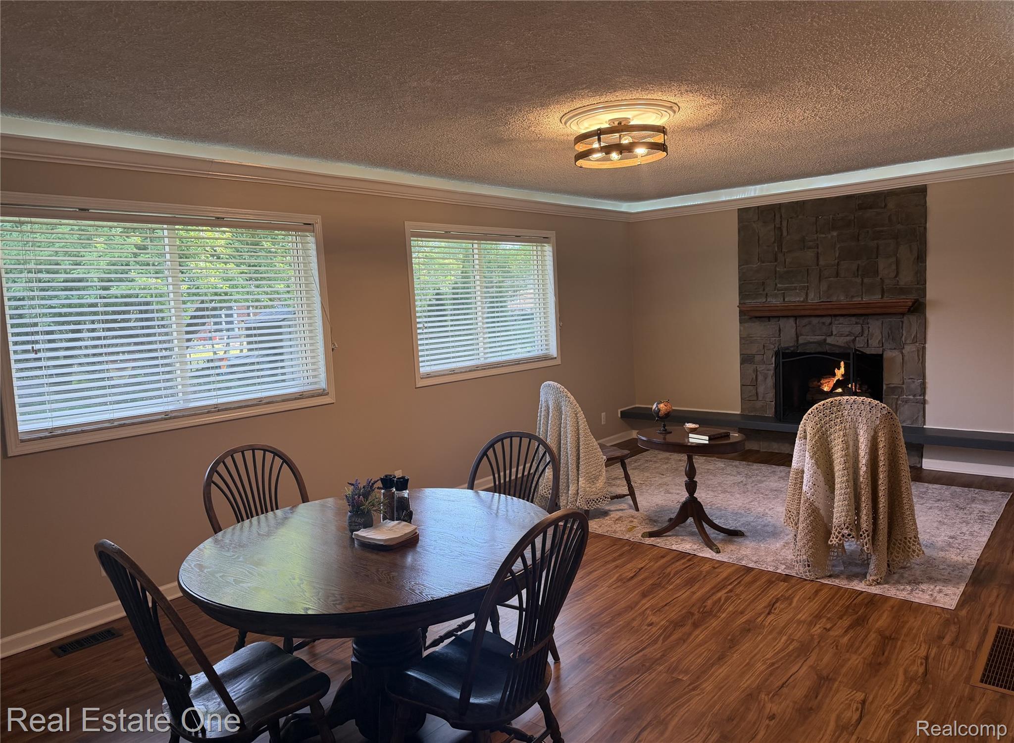 1115 Torpey Road Troy, MI 48083 - Photo 18 of 38 Living area with wood-finish flooring, a stone-clad fireplace with a hearth and wood mantel, and crown molding