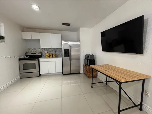 a living room with furniture a flat screen tv and kitchen view