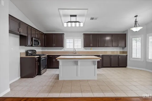 a kitchen with stainless steel appliances granite countertop a sink dishwasher stove and a refrigerator with wooden cabinets