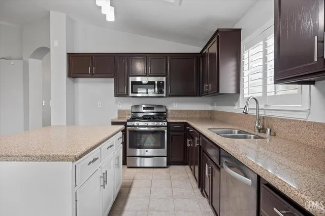 a kitchen with granite countertop a sink stove and refrigerator