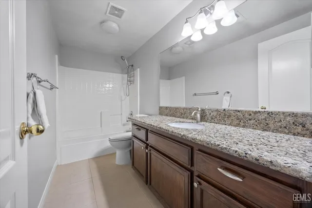a bathroom with a granite countertop sink a toilet and shower