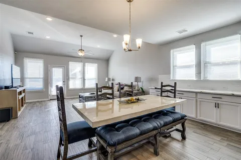 a view of a dining room and livingroom with furniture wooden floor a rug a potted plant and a chandelier