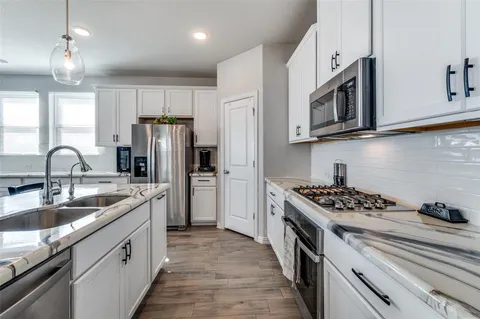 a kitchen with stainless steel appliances granite countertop a sink stove a refrigerator and cabinets with wooden floor