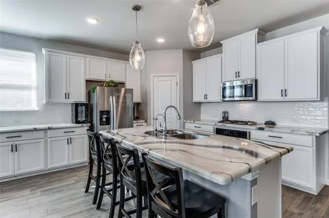 a kitchen with stainless steel appliances granite countertop a table chairs stove microwave and cabinets