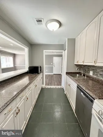 a large white kitchen with granite countertop a sink