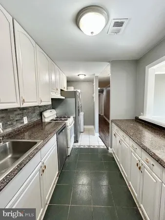 a large kitchen with stainless steel appliances granite countertop a sink stove and refrigerator