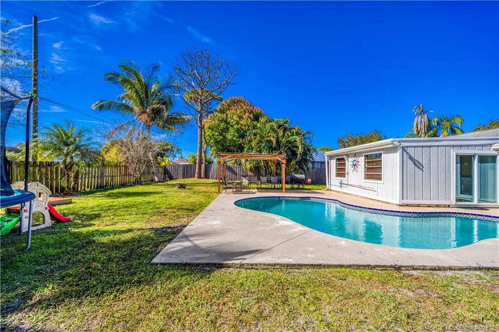 656 Southeast Ron Rico Terrace Port St. Lucie, FL 34983 - Photo 16 of 20 a view of a house with swimming pool and a yard