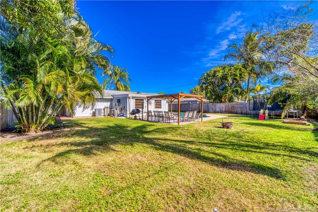 656 Southeast Ron Rico Terrace Port St. Lucie, FL 34983 - Photo 18 of 20 a view of a swimming pool with a lawn chairs under an umbrella
