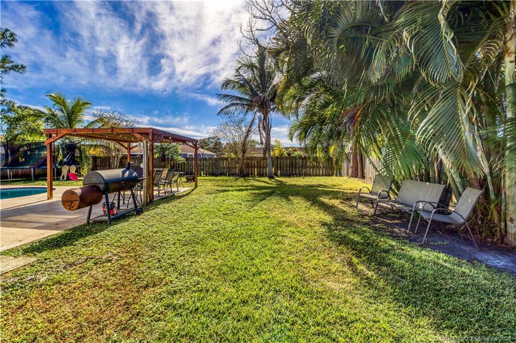 656 Southeast Ron Rico Terrace Port St. Lucie, FL 34983 - Photo 19 of 20 a view of a swimming pool with a table and chairs under an umbrella