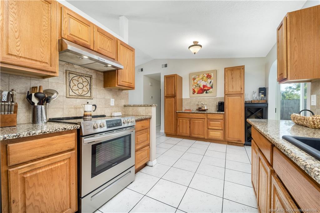 656 Southeast Ron Rico Terrace Port St. Lucie, FL 34983 - Photo 3 of 20 a kitchen with stainless steel appliances granite countertop a stove a sink and a refrigerator