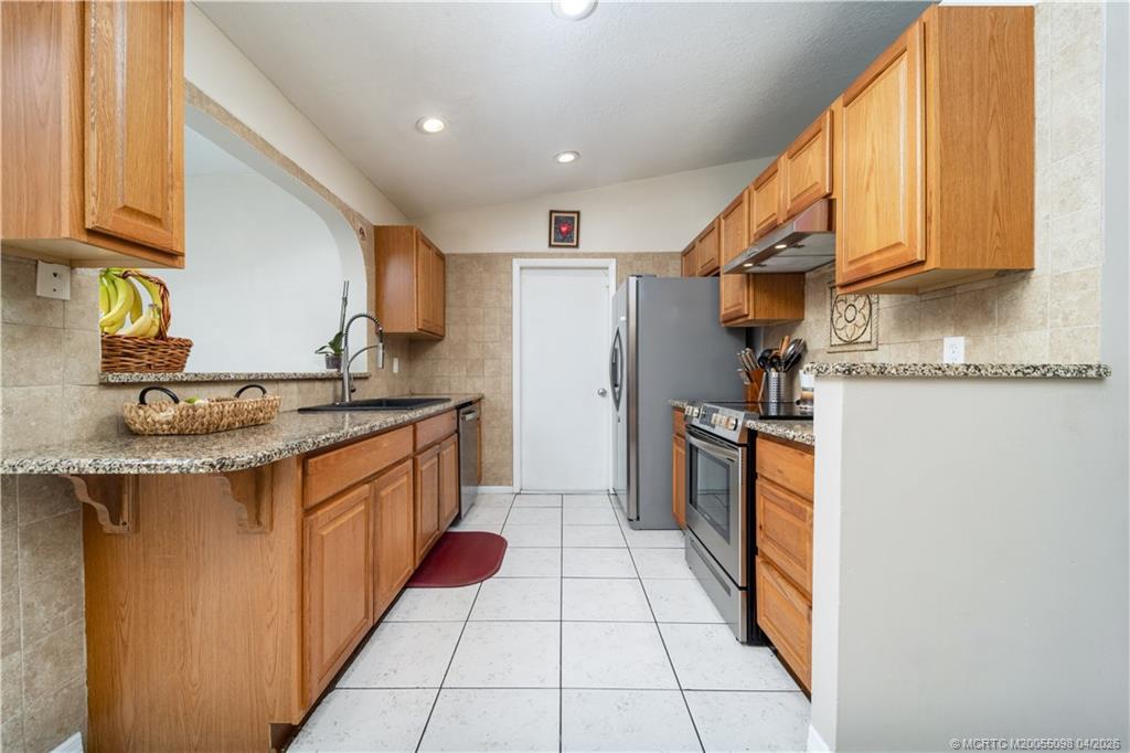 656 Southeast Ron Rico Terrace Port St. Lucie, FL 34983 - Photo 4 of 20 a kitchen with stainless steel appliances granite countertop a sink and cabinets