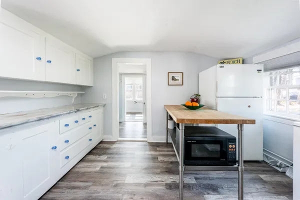 a kitchen with granite countertop white cabinets and wooden floor