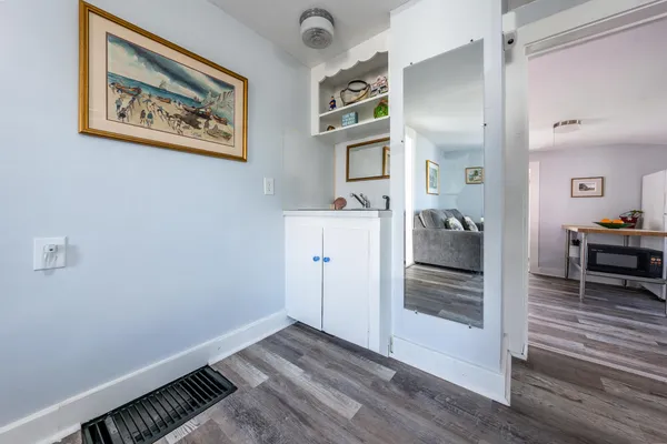 a view of a hallway with wooden floor and cabinet