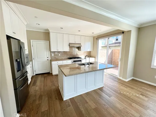 a kitchen with granite countertop a refrigerator stove top oven and sink