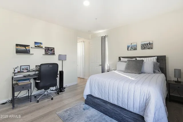 a bedroom with a bed wooden floor and a large window