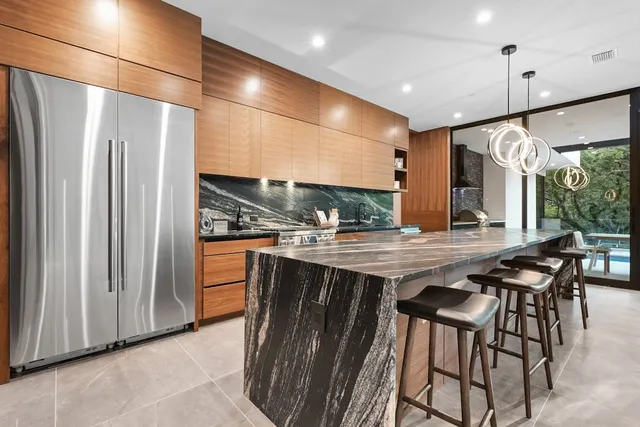 a kitchen with stainless steel appliances granite countertop table chairs and a refrigerator