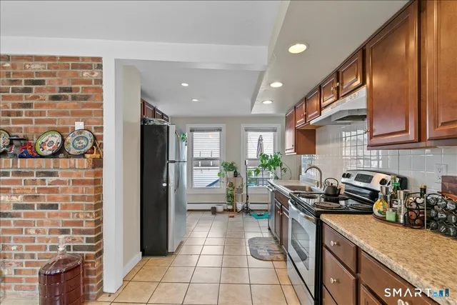 a kitchen with granite countertop a stove a sink a refrigerator and cabinets
