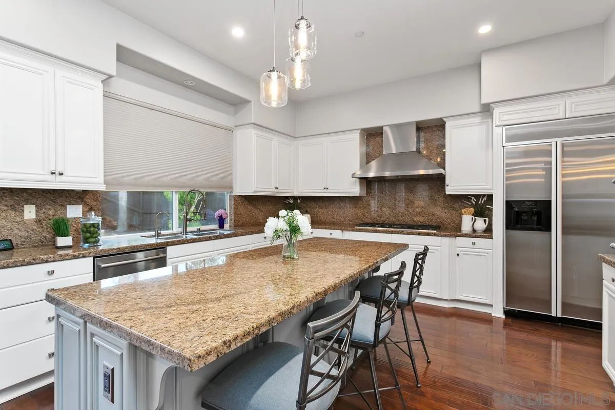 16309 Deer Ridge Road San Diego, CA 92127 - Photo 19 of 37 a kitchen with kitchen island granite countertop a table chairs stove and refrigerator