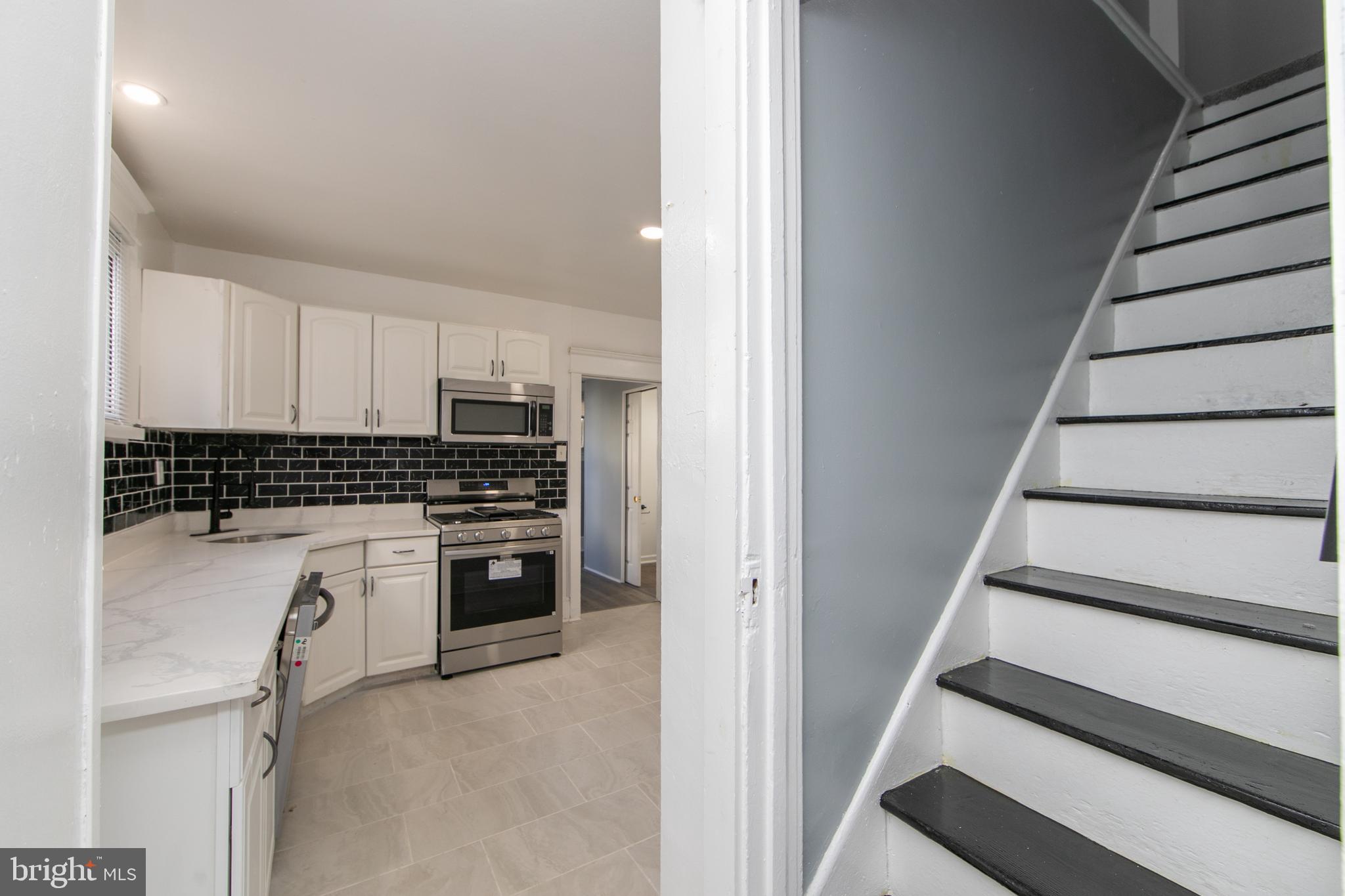 513 Benson Street Camden, NJ 08103 - Photo 8 of 37 a kitchen with white cabinets and black appliances