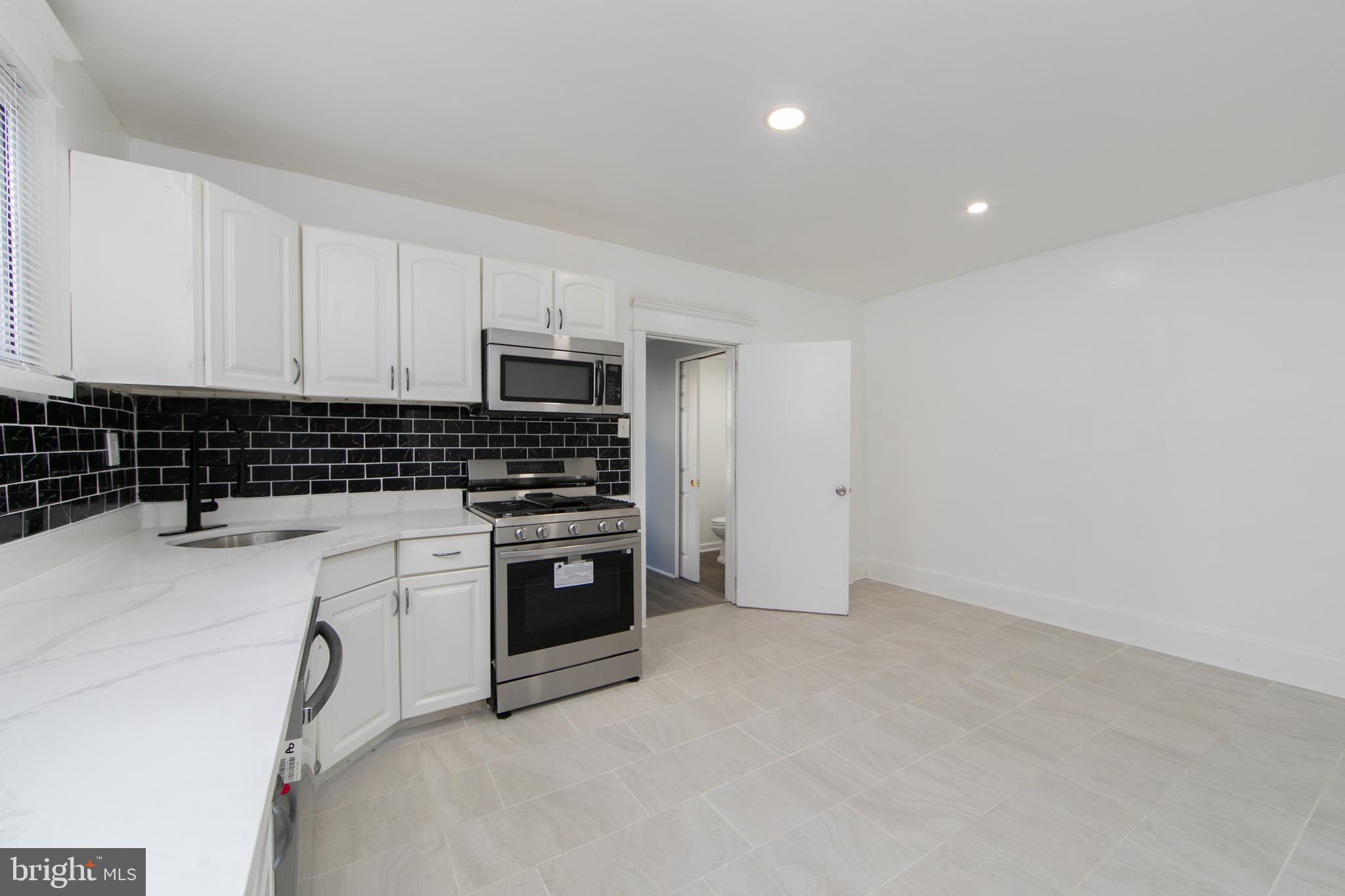 513 Benson Street Camden, NJ 08103 - Photo 9 of 37 a kitchen with granite countertop a stove sink and cabinets
