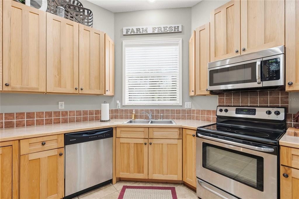 34106 Trilby Road Dade City, FL 33523 - Photo 25 of 39 a kitchen with stainless steel appliances granite countertop a sink a stove a microwave cabinets and a window
