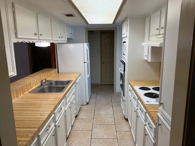 a kitchen with granite countertop a refrigerator a stove a sink and dishwasher