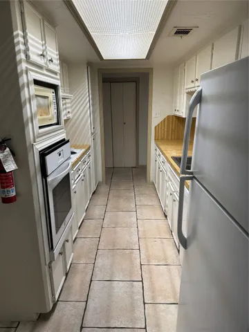 an empty room with wooden floor chandelier fan and windows
