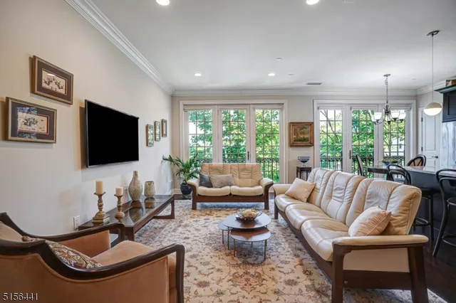 a living room with furniture floor to ceiling window hardwood floor and a flat screen tv