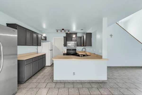 a large kitchen with stainless steel appliances a sink and a refrigerator