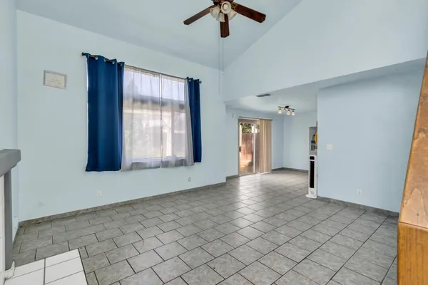 a view of an empty room with window and chandelier fan