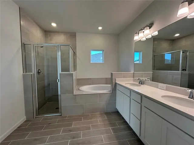 a bathroom with a double vanity sink a large mirror and a bathtub