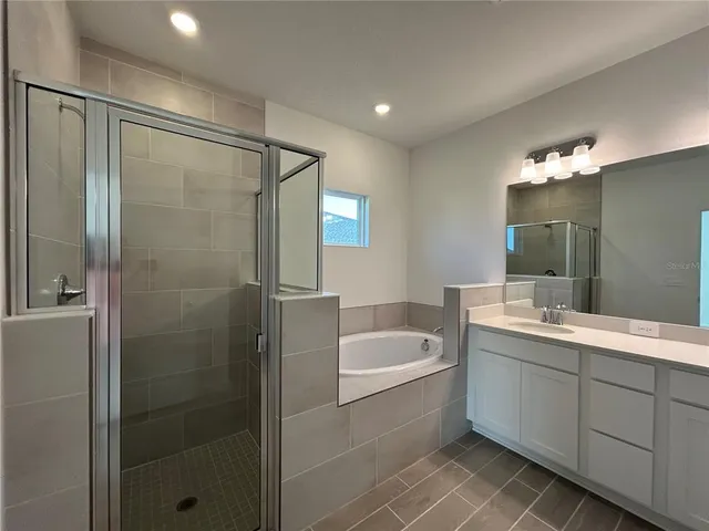 a bathroom with a tub sink shower and mirror