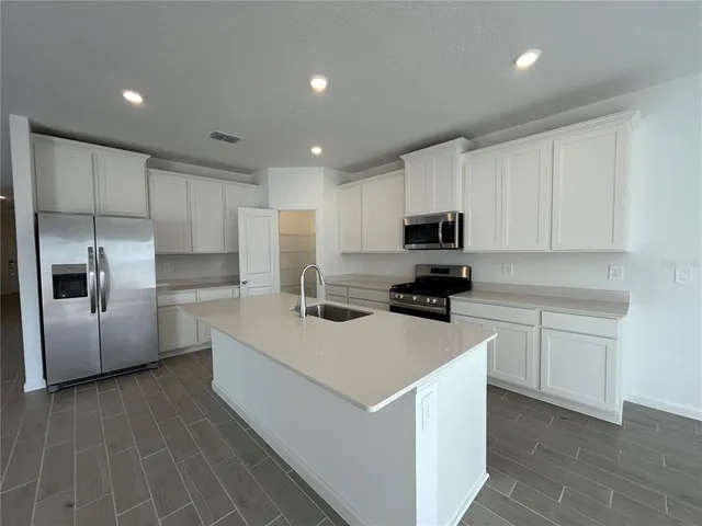 a kitchen with a sink a stove a refrigerator a microwave and cabinets
