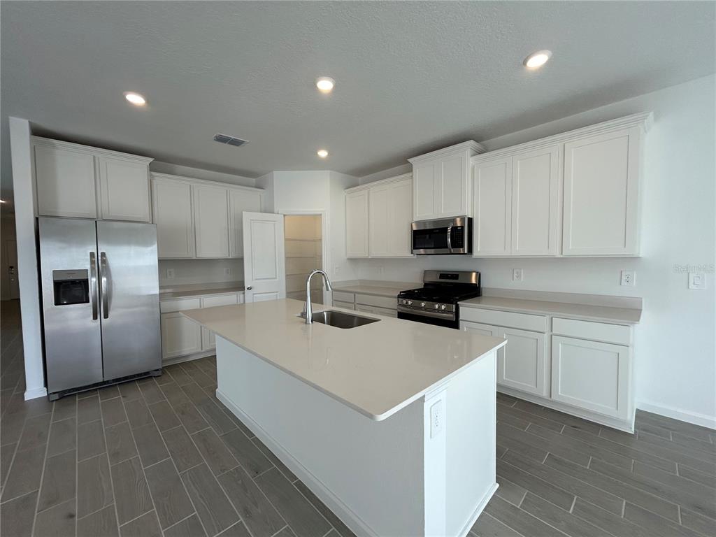12419 Northwest 139th Court Alachua, FL 32615 - Photo 4 of 38 a kitchen with a sink a stove a refrigerator a microwave and cabinets