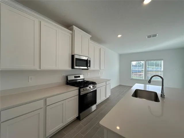 a kitchen with white cabinets a sink and appliances